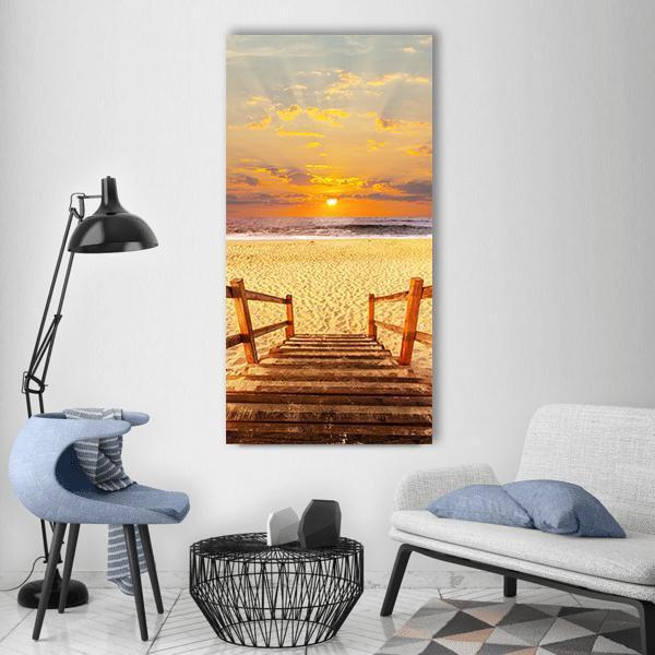 Sunset Boardwalk on Beach Vertical Canvas Wall Art in beige, orange and yellow, single vertical panel hung on a wall