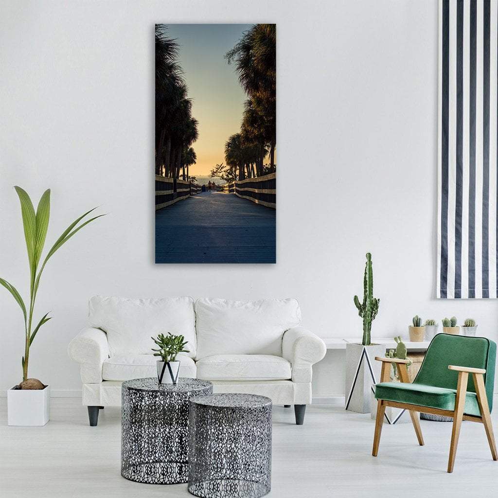 Boardwalk with Palm Trees at Sunset Vertical Canvas Wall Art in black, orange and blue, single vertical panel hung on a wall