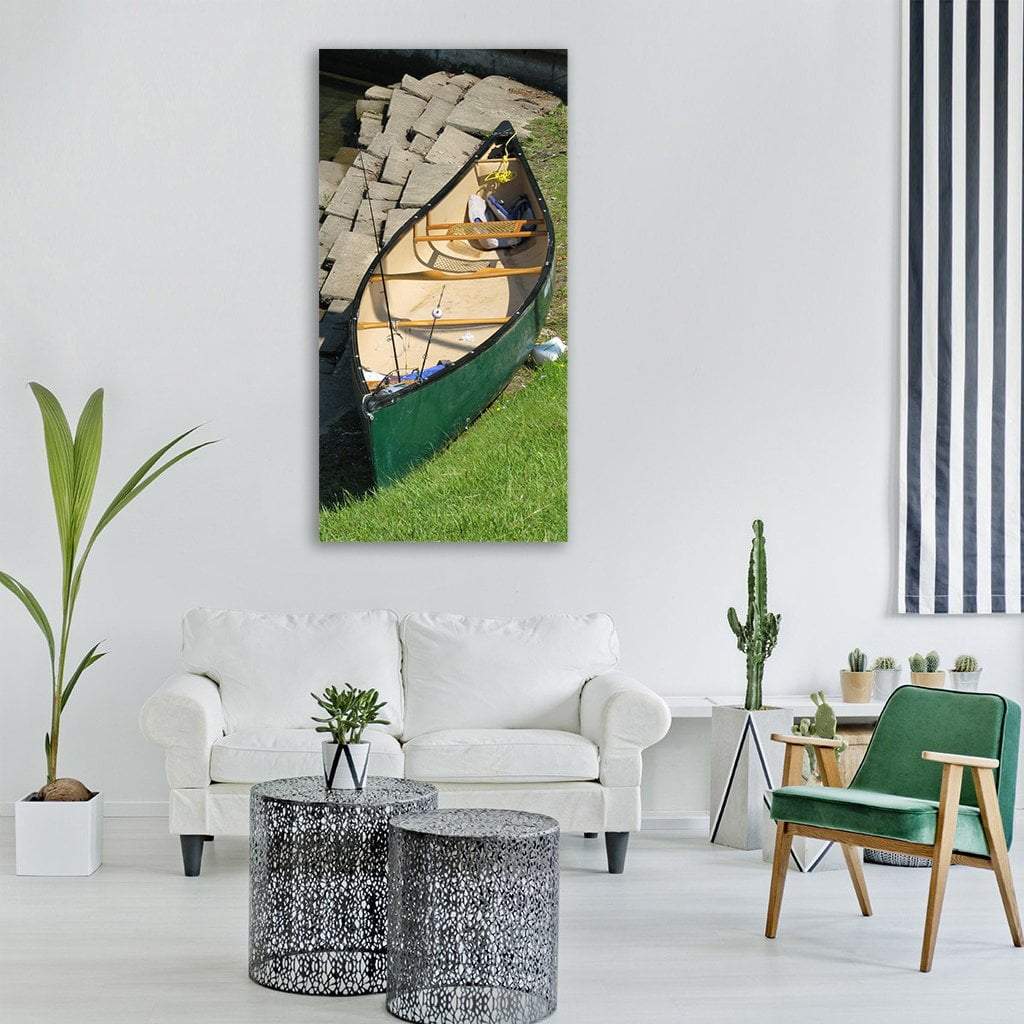 Canoe with Two Fishing Rods on Shore Vertical Canvas Wall Art in gray, beige and green, hung on a wall