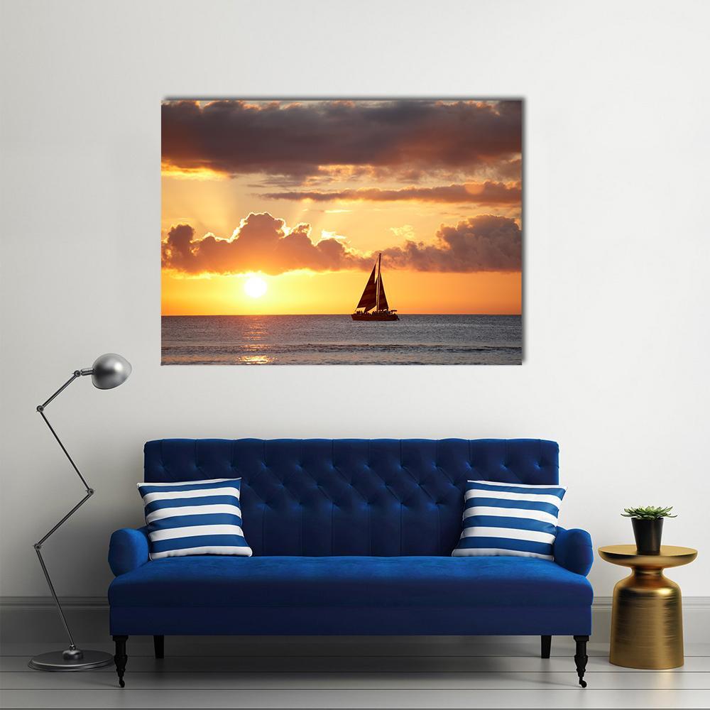 Sailboat at Sunset Over Ocean Canvas Wall Art in orange, yellow and blue, single panel hung on a wall