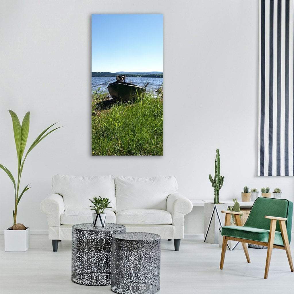 Weathered Wooden Boat on Lake Shore Vertical Canvas Wall Art in brown, green and blue, single vertical panel hung on a wall