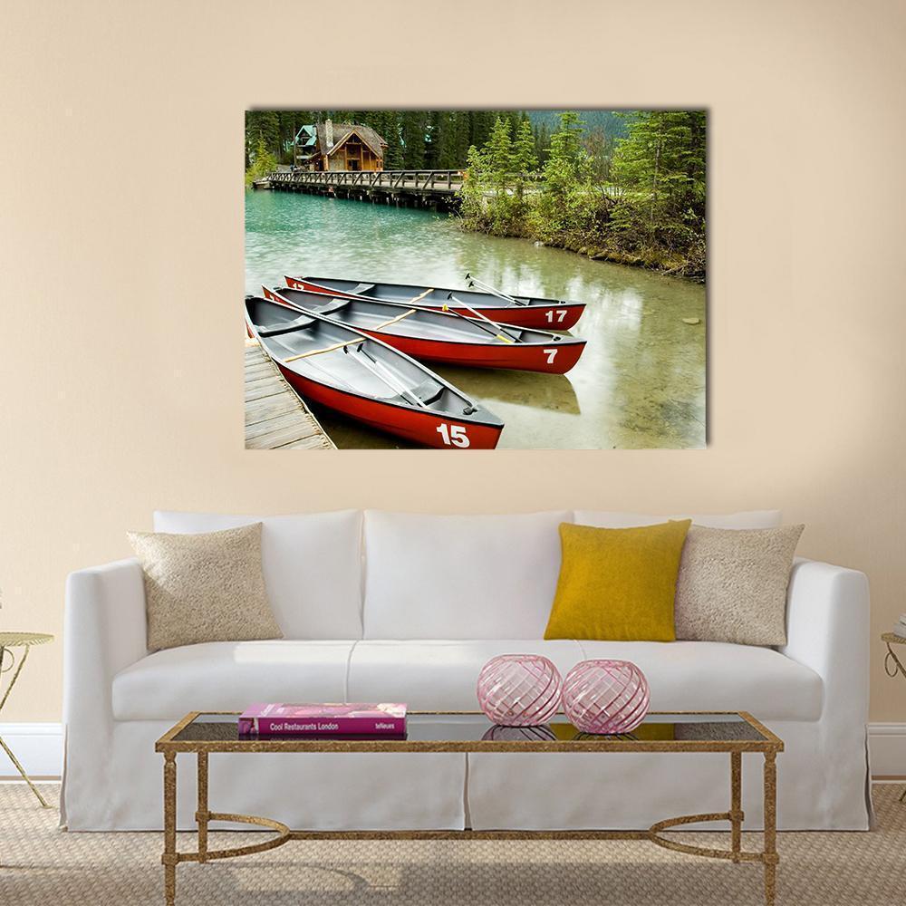 Red Canoes on Emerald Lake Canvas Wall Art in red, green and blue, single panel hung on a wall