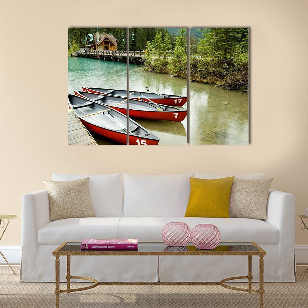 Red Canoes on Emerald Lake Canvas Wall Art in brown, red and green, 3 panel horizontal set hung on a wall