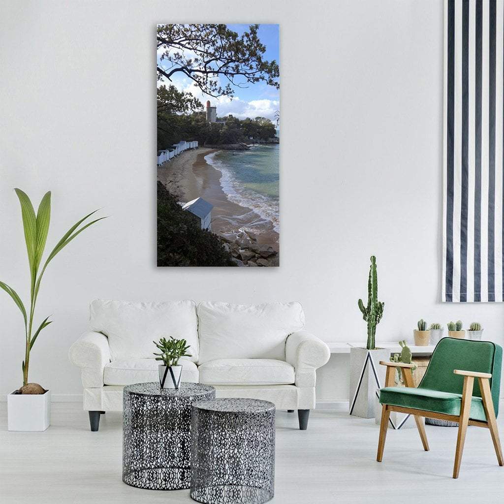 Beach with White Cabanas and Lighthouse Vertical Canvas Wall Art in beige, green and blue, single vertical panel hung on a wall