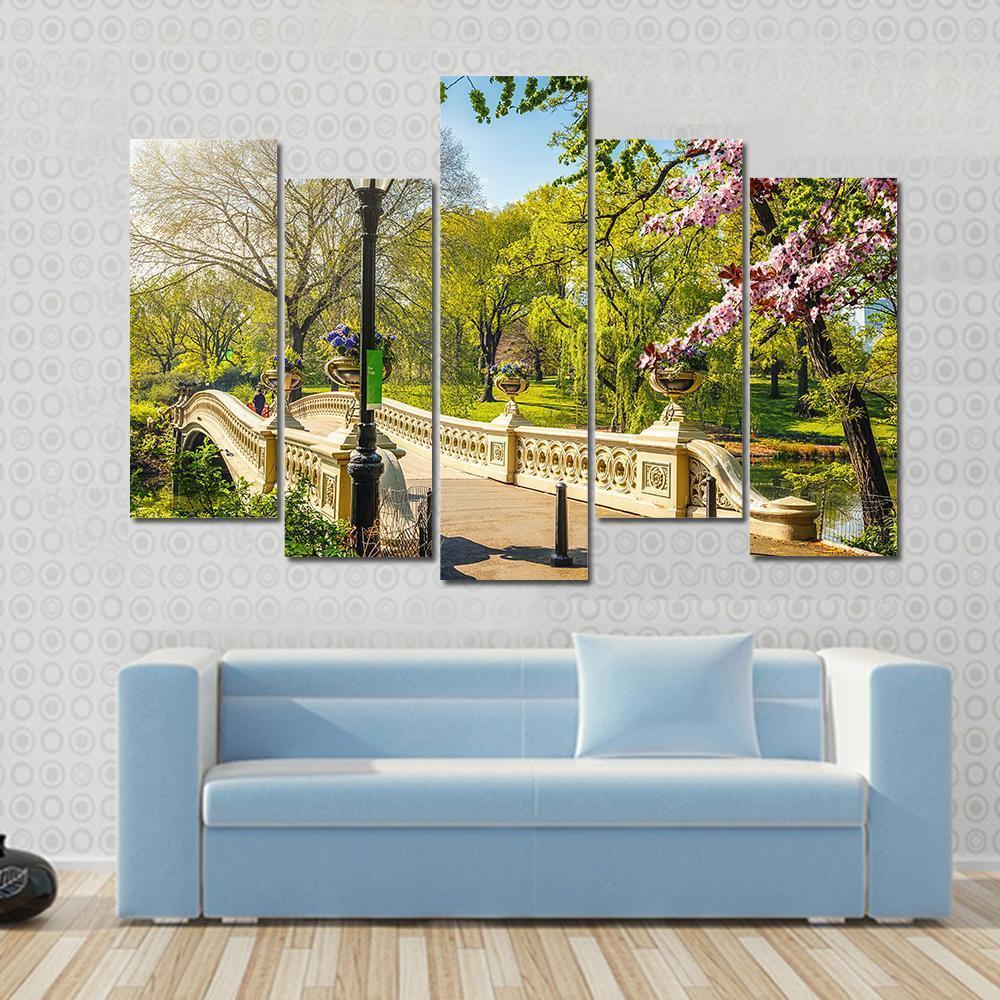 Bow Bridge in Central Park Canvas Wall Art in beige, green and blue, single panel hung on a wall
