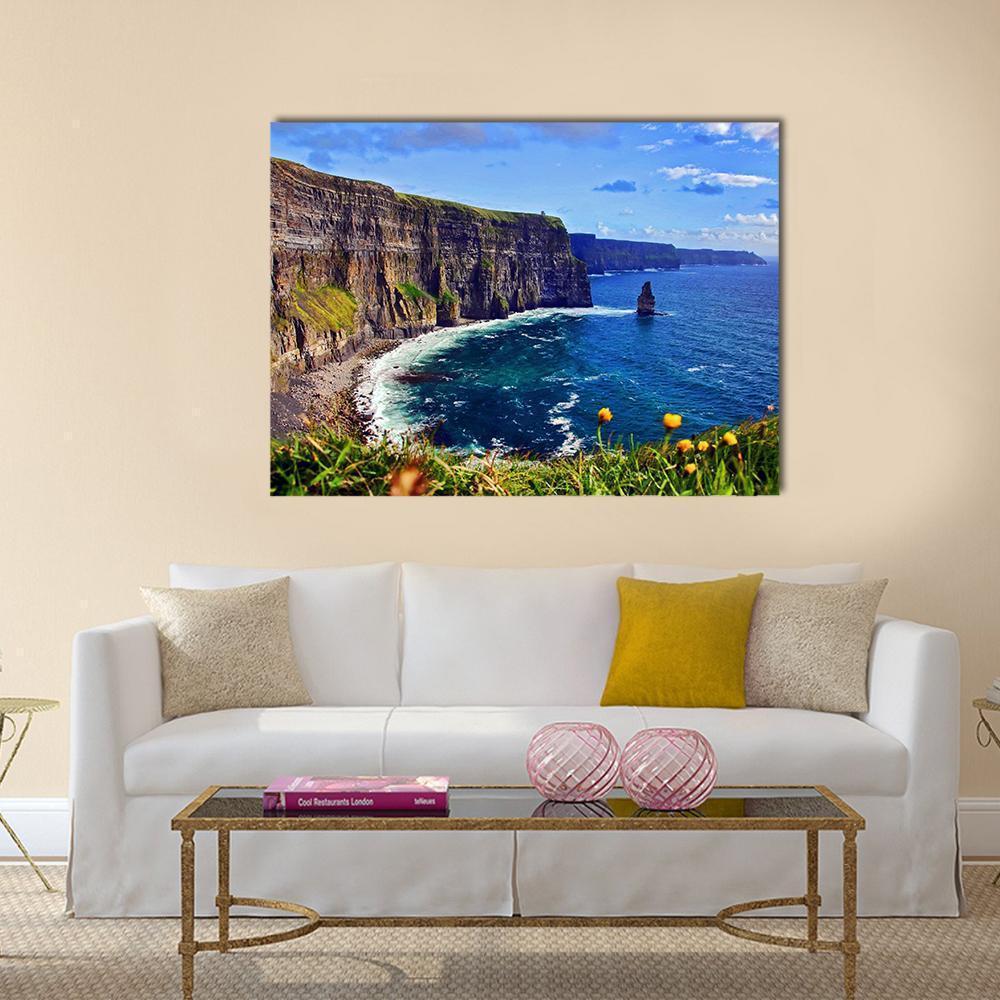 Coastal Cliffs with Sea Stack and Wildflowers Canvas Wall Art in brown, green and blue, single panel hung on a wall