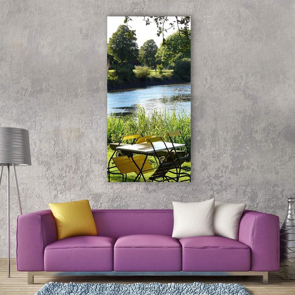Bremen Lake Riverbank with Yellow Chairs Vertical Canvas Wall Art in yellow, green and blue, single vertical panel hung on a wall