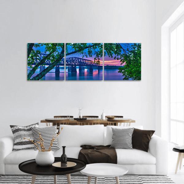 Truss Bridge Over River at Dusk Panoramic Canvas Wall Art in green, blue and purple, hung on a wall