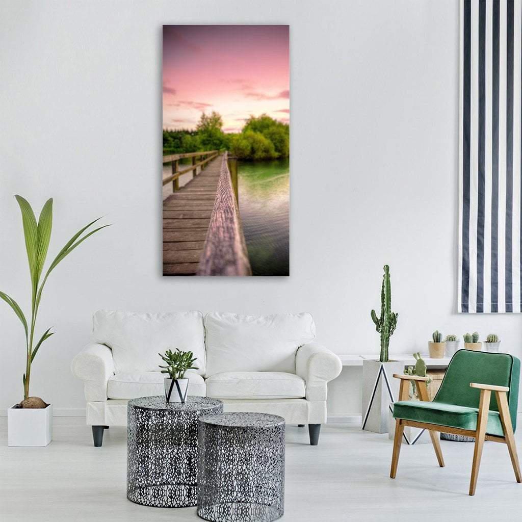 Wooden Bridge Over Lake at Sunset Vertical Canvas Wall Art in brown, green and pink, single vertical panel hung on a wall