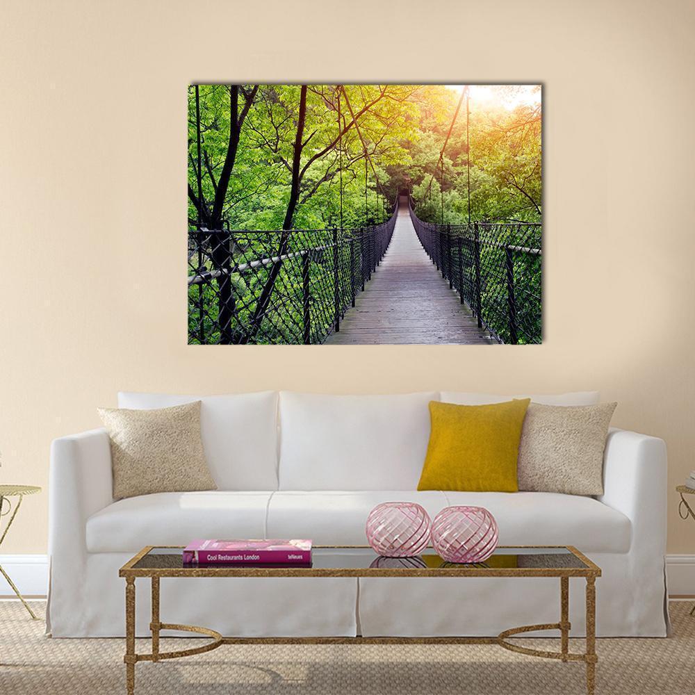 Sunlit Jungle Suspension Bridge Canvas Wall Art in brown, yellow and green, single panel hung on a wall