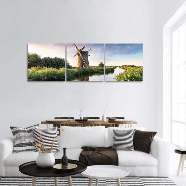 Brograve Windmill, England Panoramic Canvas Wall Art in brown, green and blue, hung on a wall