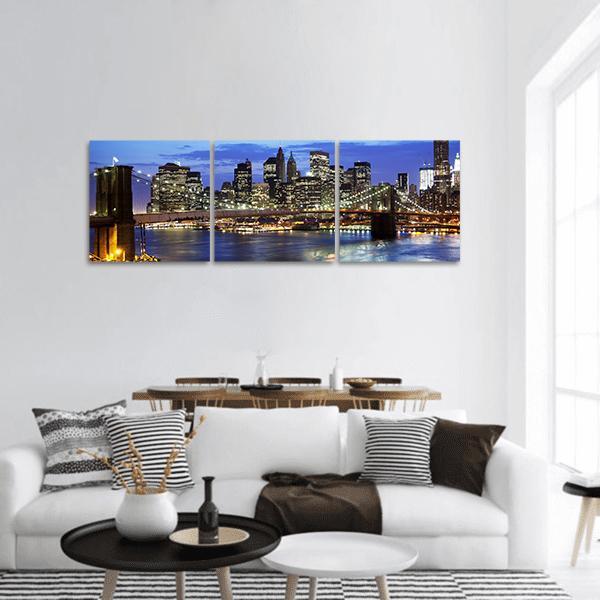 Brooklyn Bridge at Night Panoramic Canvas Wall Art in black, yellow and blue, hung on a wall