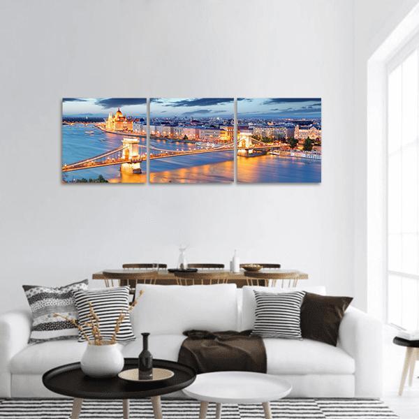 Budapest Night Skyline with Chain Bridge and Parliament Panoramic Canvas Wall Art in gold, orange and blue, hung on a wall