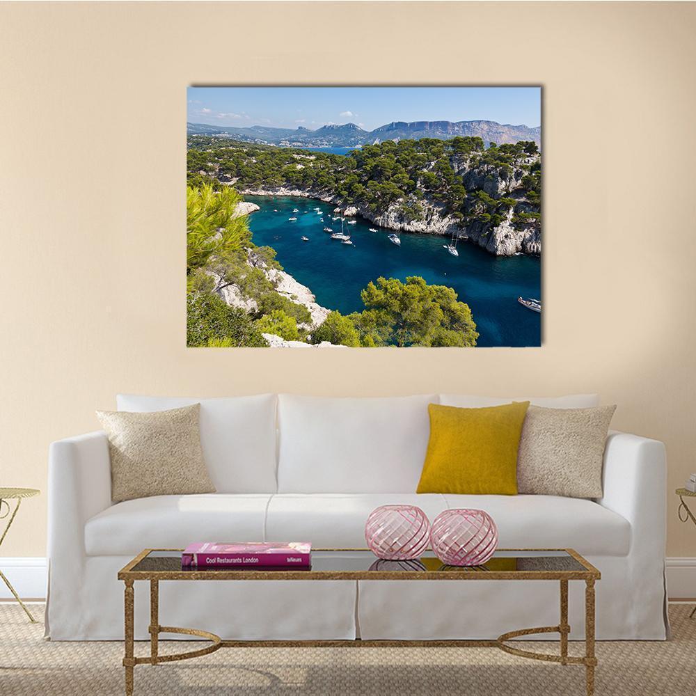 Rocky Coast with Pine Trees and Sailboats Canvas Wall Art in green and blue, single panel hung on a wall