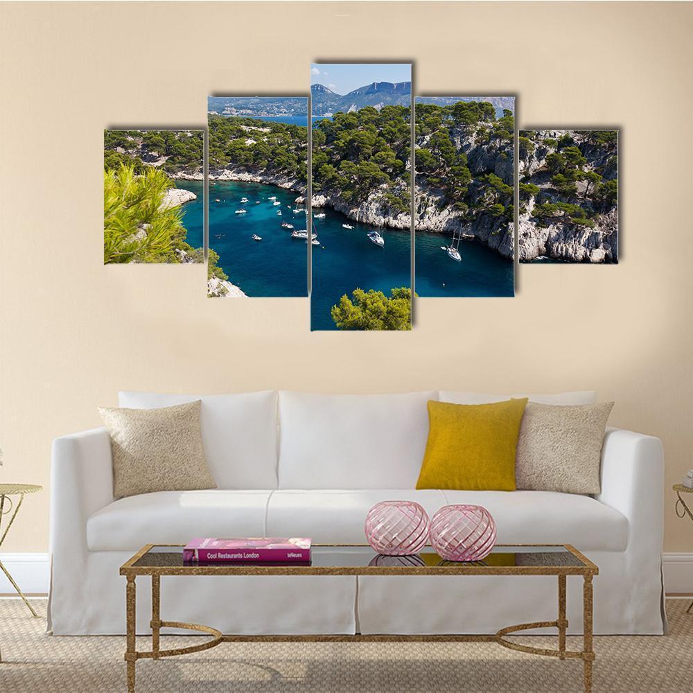 Rocky Coast with Pine Trees and Sailboats Canvas Wall Art in green and blue, 5 panel Star layout hung on a wall