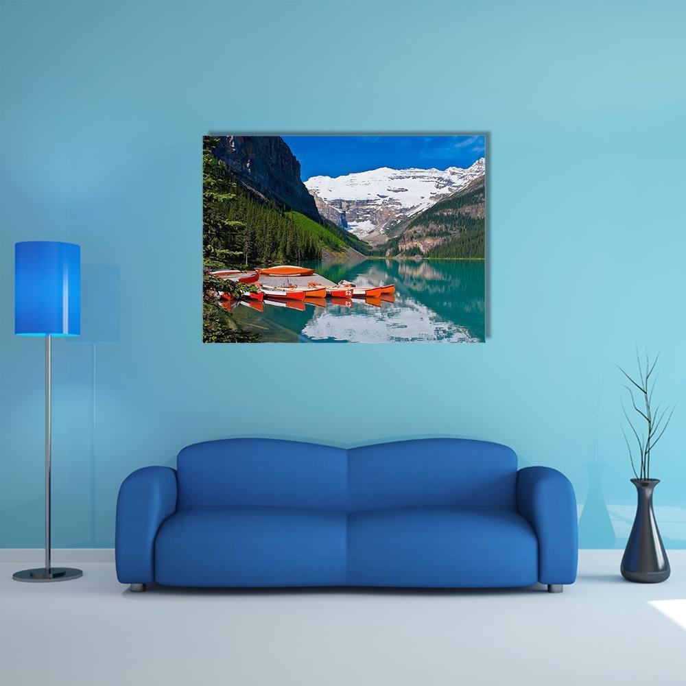 Orange Canoes on Alpine Lake Canvas Wall Art in orange, green and blue, single panel hung on a wall