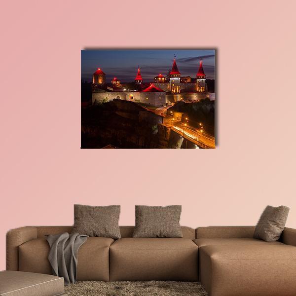 Illuminated Castle with Bridge at Night Canvas Wall Art in black, orange and blue, single panel hung on a wall