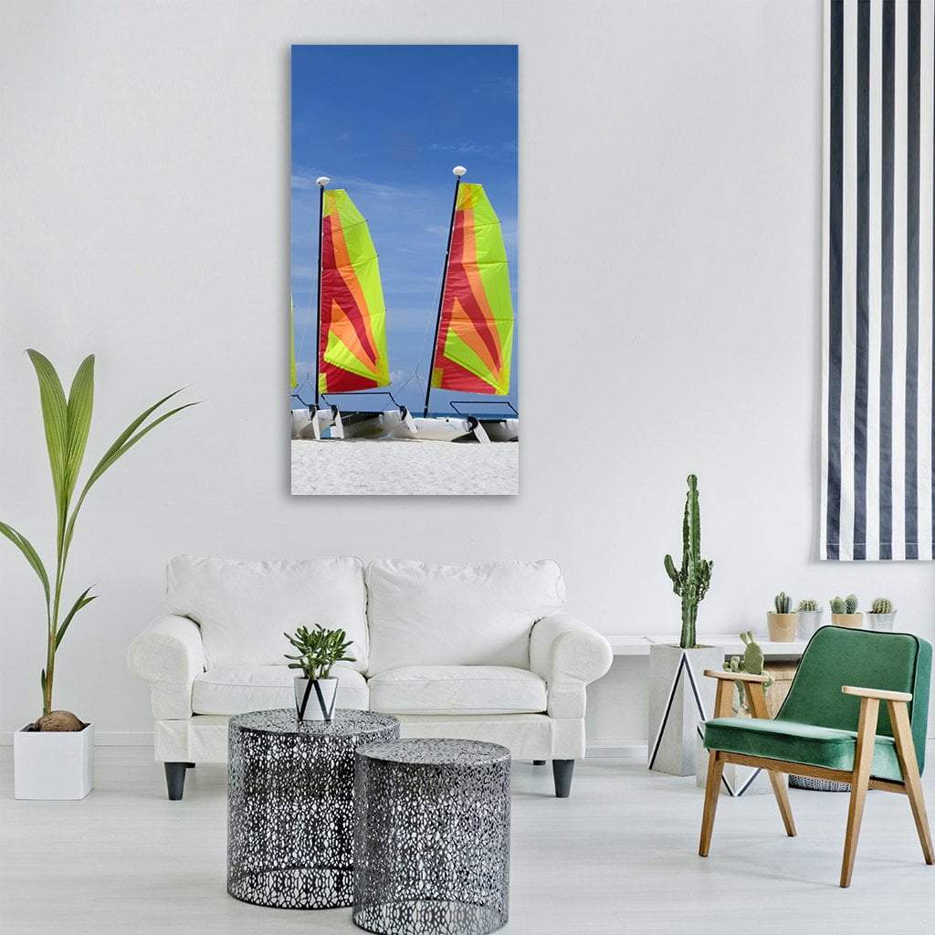 Two Catamarans with Vibrant Striped Sails Vertical Canvas Wall Art in red, yellow and blue, hung on a wall