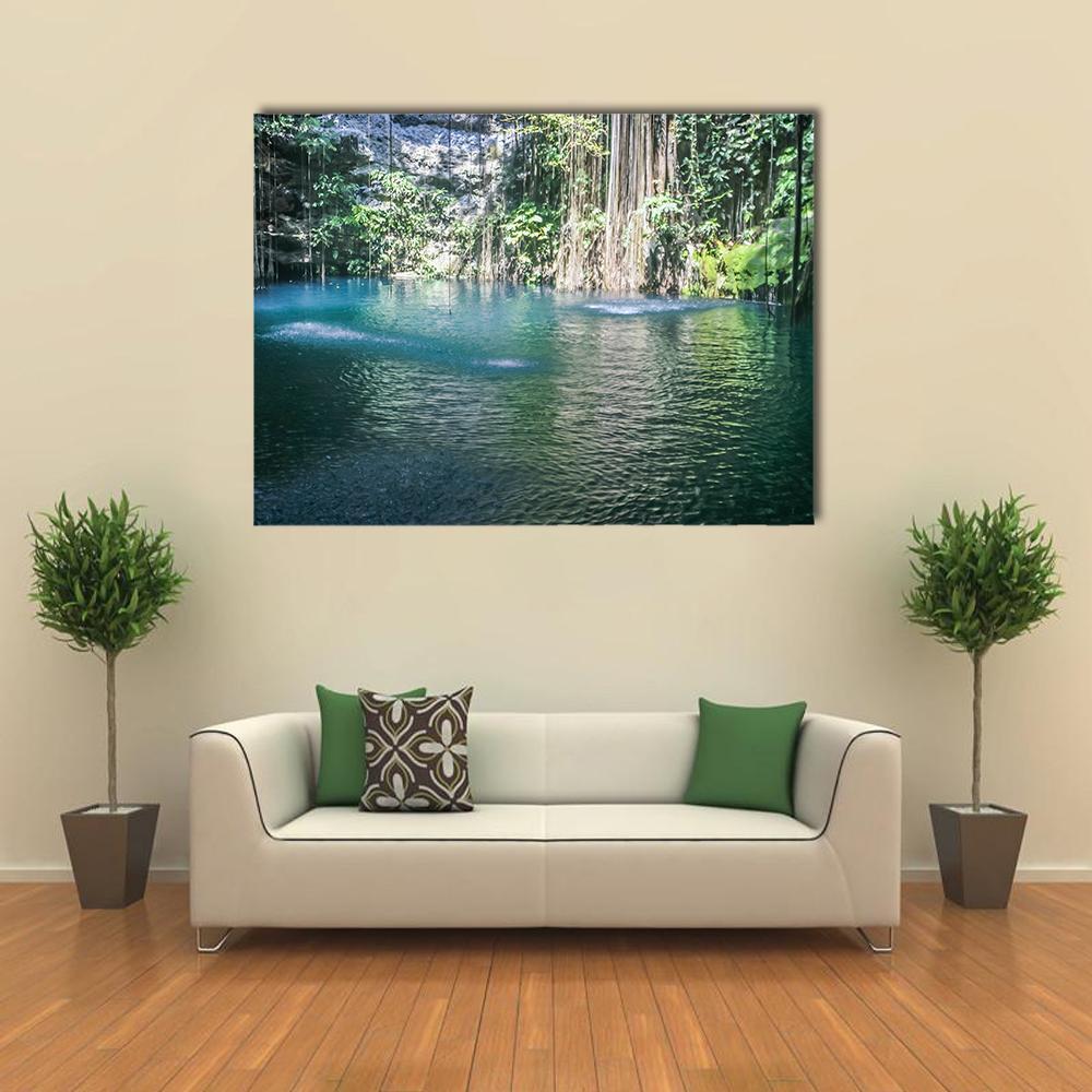 Sunlit Cenote with Hanging Vines Canvas Wall Art in green and blue, single panel hung on a wall