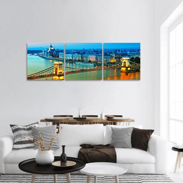 Chain Bridge and Hungarian Parliament at Twilight Panoramic Canvas Wall Art in gold, yellow and blue, hung on a wall