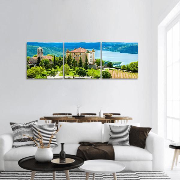 Hilltop Church Over Lake and Vineyard Panoramic Canvas Wall Art in beige, green and blue, hung on a wall