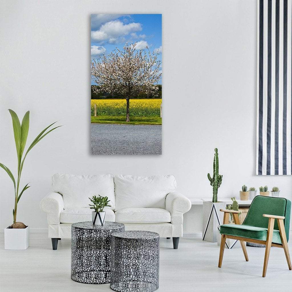 Cherry Tree Beside Gravel Road Vertical Canvas Wall Art in gray, yellow and blue, hung on a wall