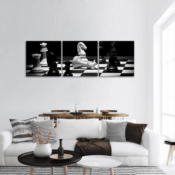 Fallen White King on Chessboard Panoramic Canvas Wall Art in black, white and gray, hung on a wall