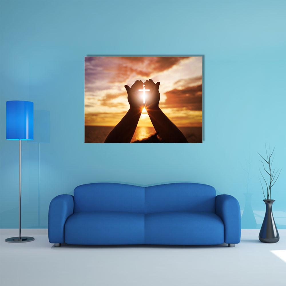 Praying Hands with Glowing Cross at Sunset Canvas Wall Art in black, orange and yellow, single panel hung on a wall
