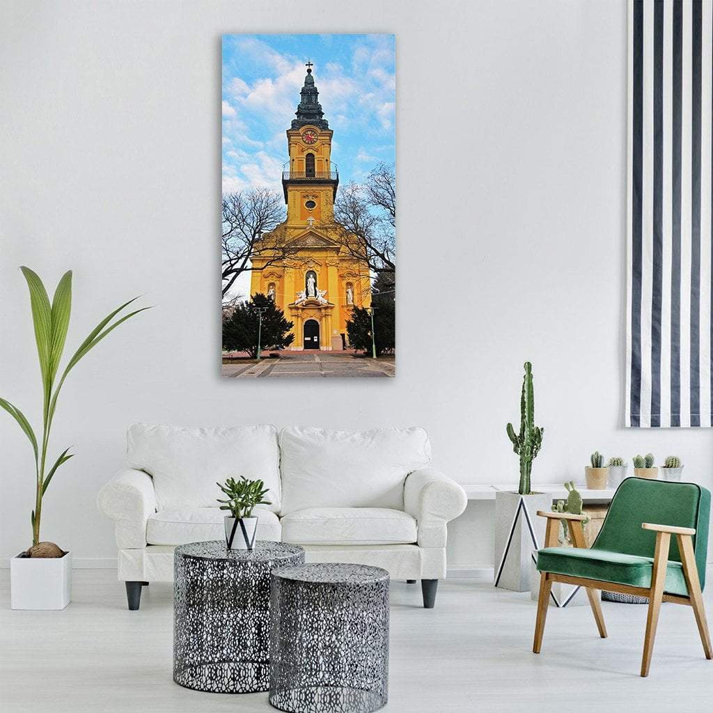Church in Hungary with Clock Tower Vertical Canvas Wall Art in gold, yellow and blue, single vertical panel hung on a wall