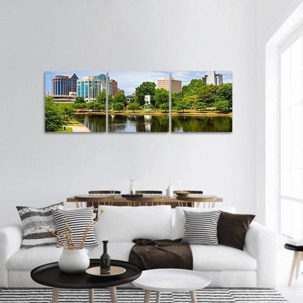 City Skyline Over Park Pond with White Gazebo Panoramic Canvas Wall Art in white, green and blue, hung on a wall