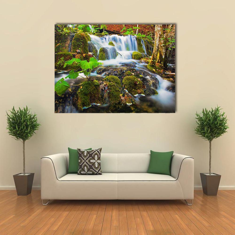 Tranquil Waterfall in Green Forest Canvas Wall Art in white, brown and green, single panel hung on a wall