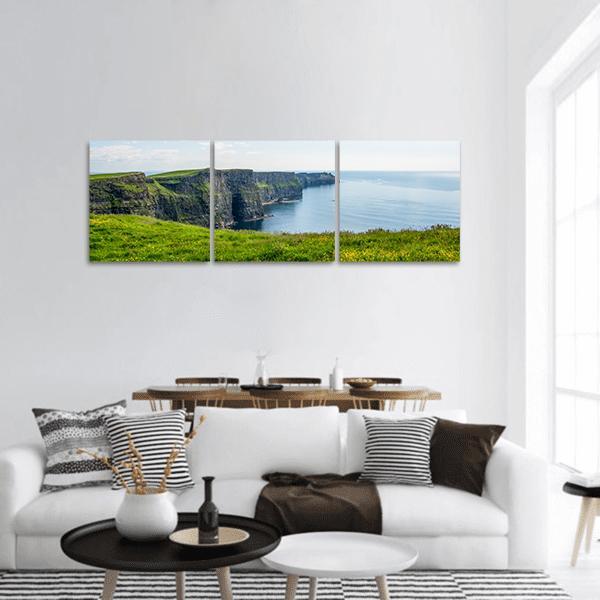 Coastal Cliffs with Grassy Clifftop Panoramic Canvas Wall Art in white, green and blue, hung on a wall