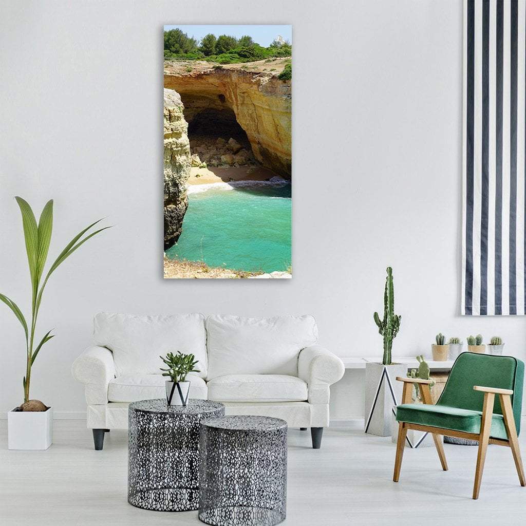 Turquoise Cove Beneath Golden Cliffs Vertical Canvas Wall Art in beige, gold and blue, single vertical panel hung on a wall