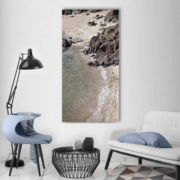 Sandy Beach with Rocky Coastline Vertical Canvas Wall Art in gray, beige and brown, single vertical panel hung on a wall