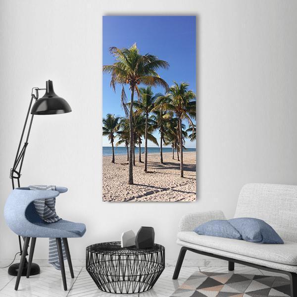 Sunny Palm Trees on Sandy Beach Vertical Canvas Wall Art in beige, green and blue, single vertical panel hung on a wall