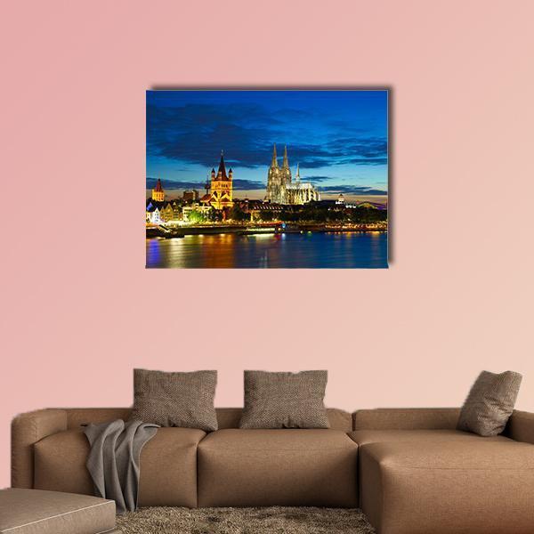 Cologne Riverfront at Dusk Canvas Wall Art in orange, yellow and blue, single panel hung on a wall