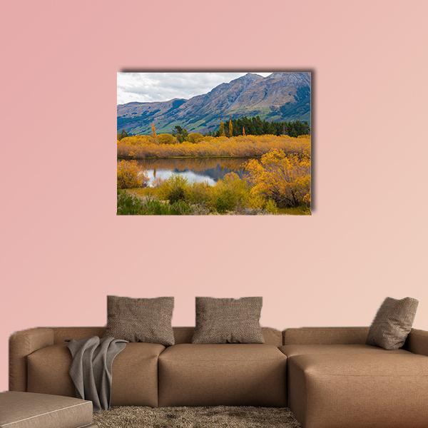 Autumn Leaves at Mountain Lake Canvas Wall Art in orange, yellow and blue, single panel hung on a wall