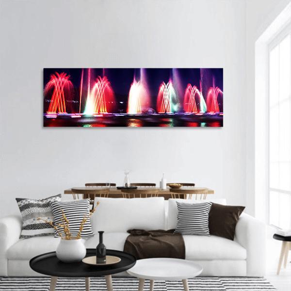 Colorful Fountain at Night Panoramic Canvas Wall Art in black, red and multicolor, single panel hung on a wall