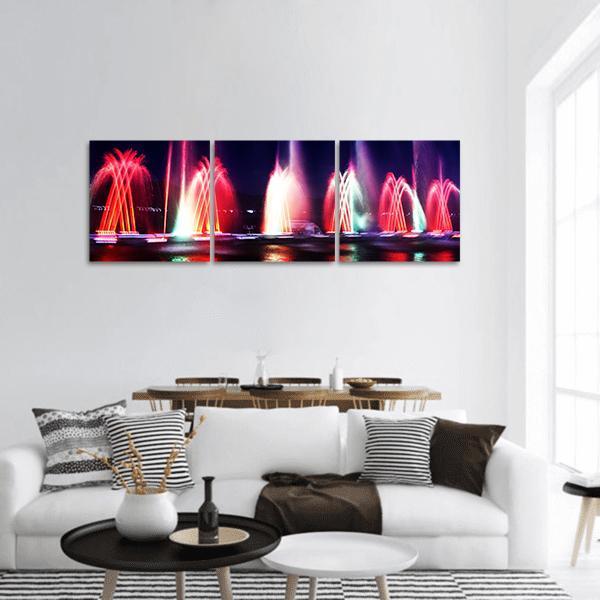 Colorful Fountain at Night Panoramic Canvas Wall Art in black, red and multicolor, hung on a wall