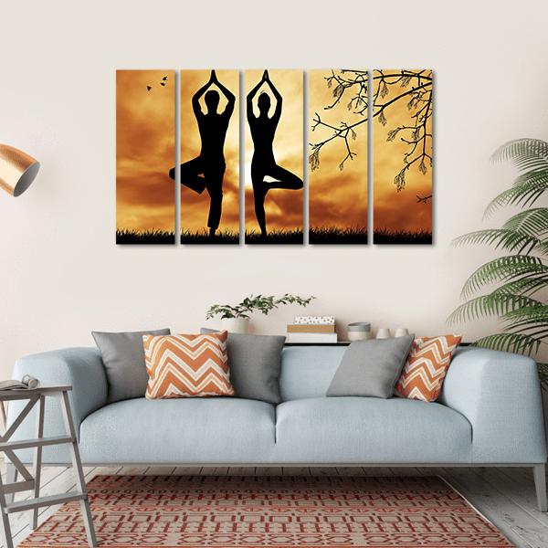 Mirrored Yoga Tree Silhouttes at Sunset Canvas Wall Art in black, orange and yellow, hung on a wall
