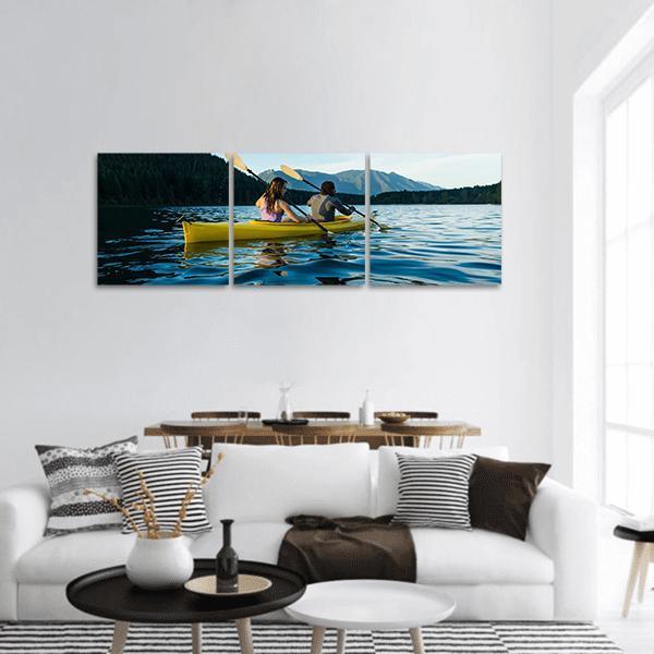 Couple Paddling on Lake Panoramic Canvas Wall Art in yellow, green and blue, hung on a wall