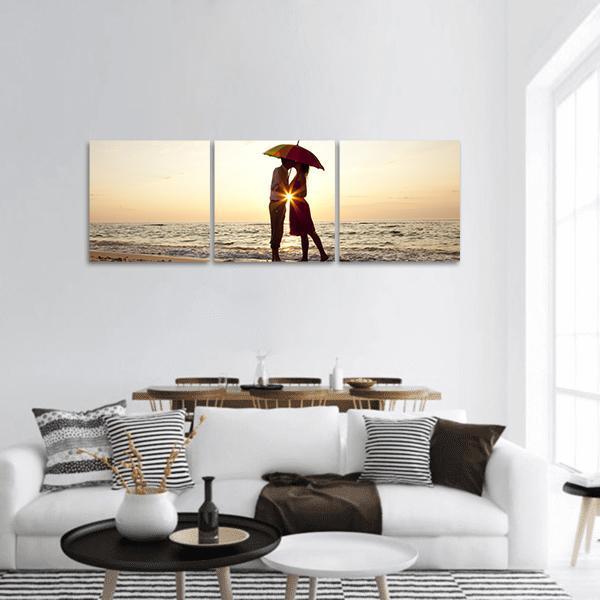 Couple Under Rainbow Umbrella at Sunset Panoramic Canvas Wall Art in beige, orange and yellow, hung on a wall