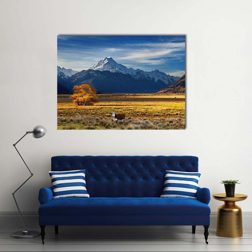 Cow by Snow-capped Mountain Canvas Wall Art in white, yellow and blue, single panel hung on a wall