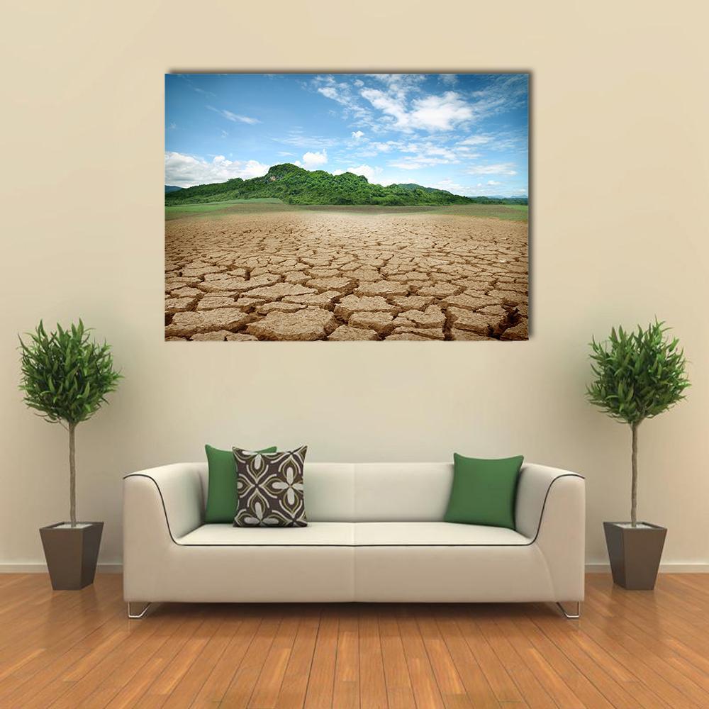 Desolate Cracked Earth in Serene Landscape Canvas Wall Art in brown, green and blue, single panel hung on a wall