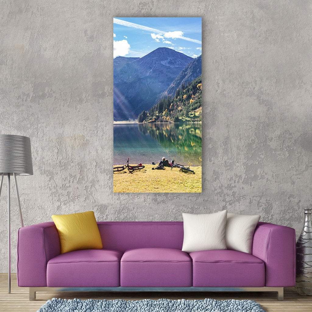 Cyclists Resting by Mountain Lake Vertical Canvas Wall Art in yellow, green and blue, single vertical panel hung on a wall