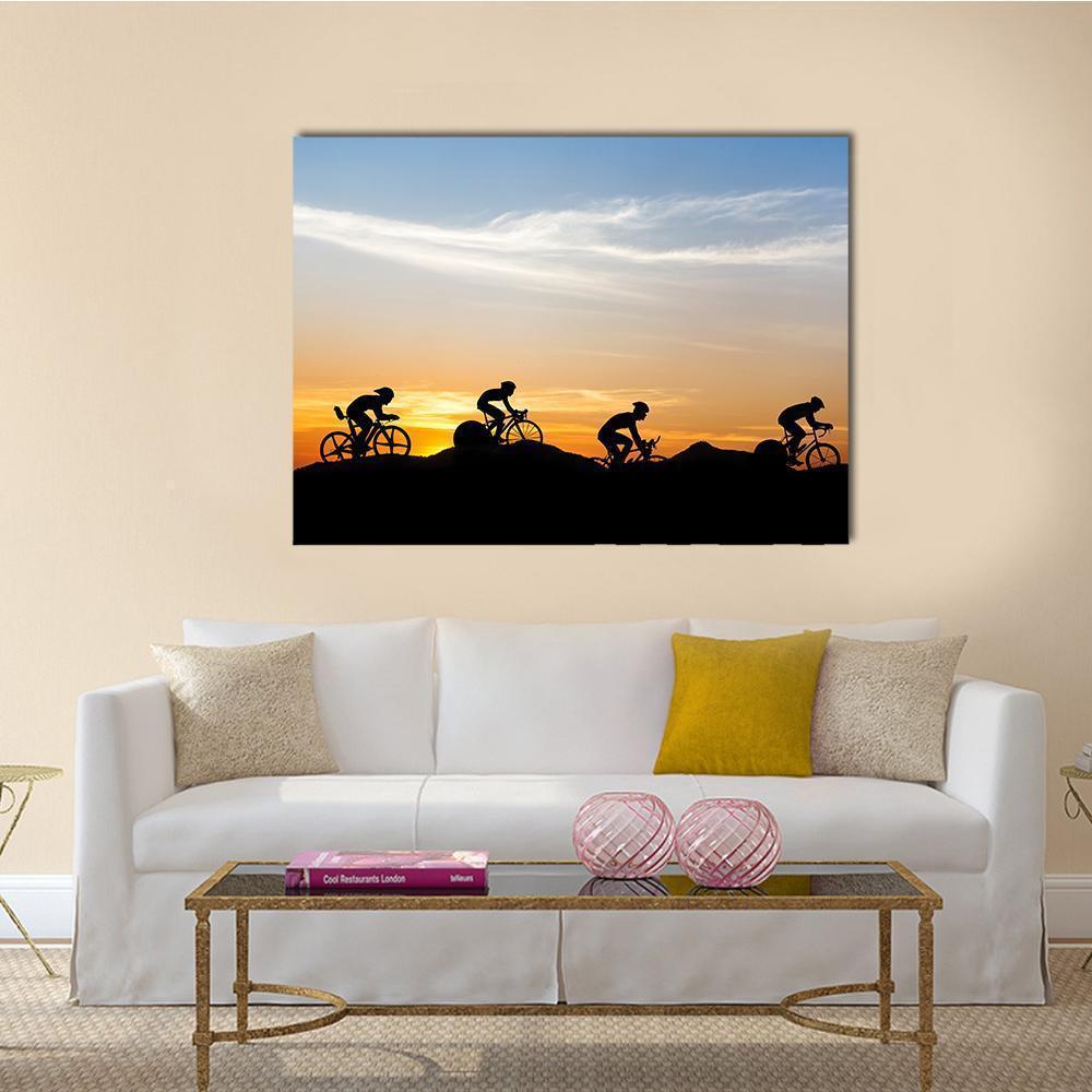 Silhouetted Cyclists at Mountain Sunset Canvas Wall Art in black, orange and blue, single panel hung on a wall