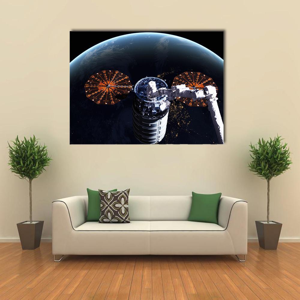 Cygnus Spacecraft Above Earth Canvas Wall Art in black, orange and blue, single panel hung on a wall