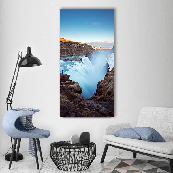 Dangerous Waterfall with Lone Figure Vertical Canvas Wall Art in white, brown and blue, single vertical panel hung on a wall