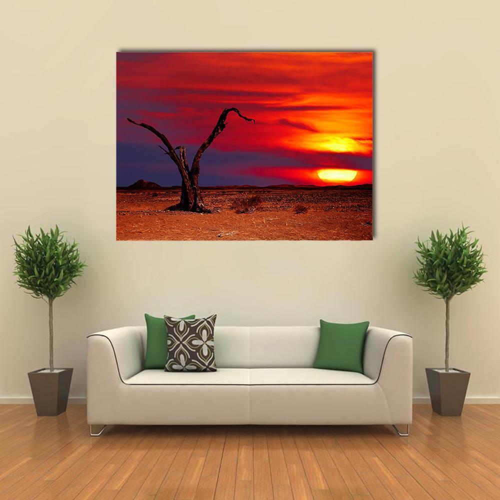 Dead Tree at Desert Sunset Canvas Wall Art in red, orange and yellow, single panel hung on a wall