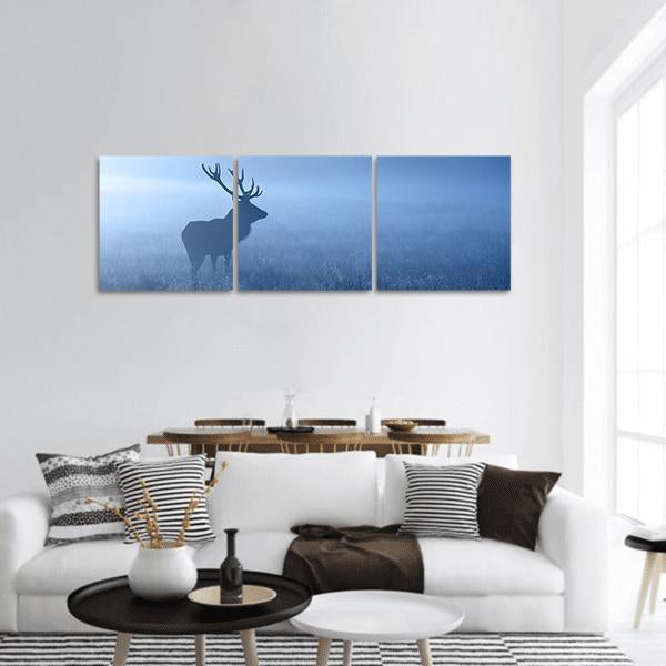 Stag Silhouette in Morning Fog Panoramic Canvas Wall Art in white and blue, hung on a wall